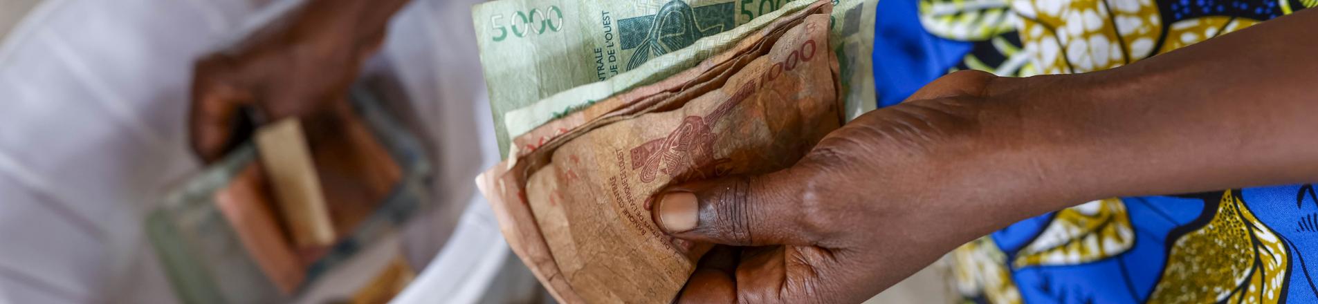 someone paying for their microfinance loan in cash, reflecting the focus of this podcast on the topic of microcredit