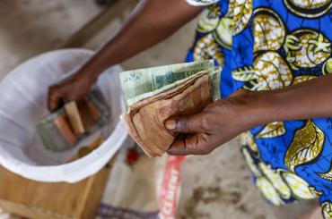 someone paying for their microfinance loan in cash, reflecting the focus of this podcast on the topic of microcredit